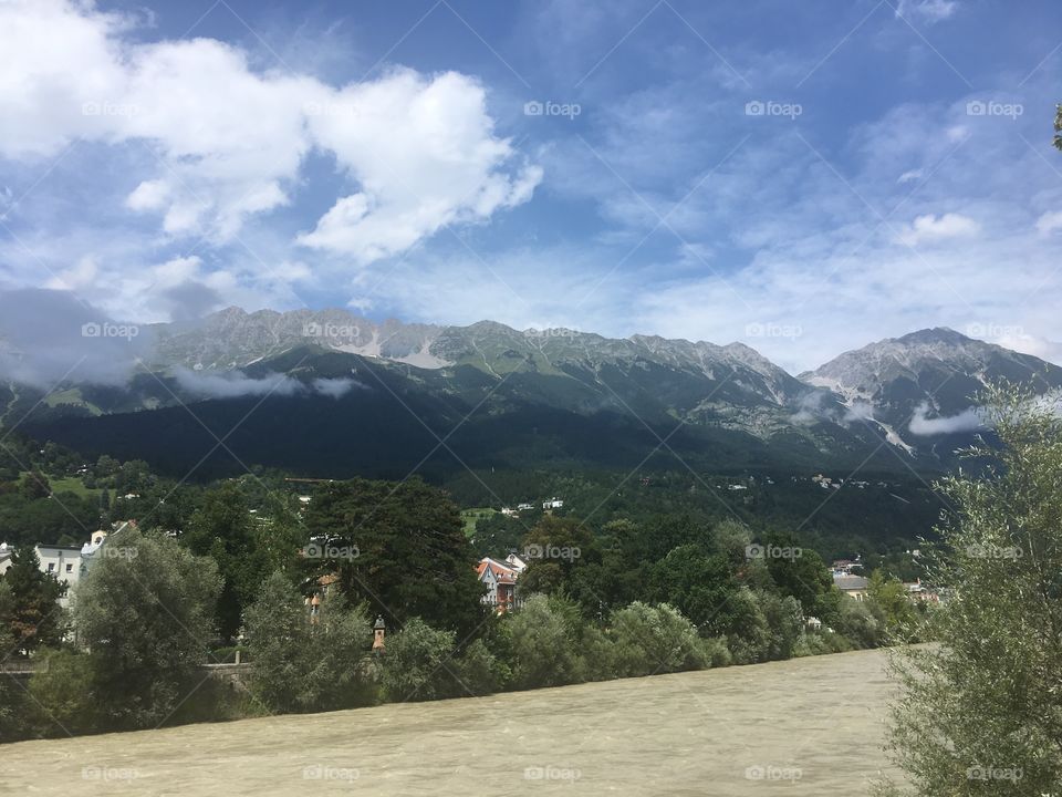A view across the river Inn of the beautiful Austrian city of Innsbruck. The amazing landscape can be seen far into the distance, with the clear air. The enormous mountains tower over the city, casting it into shadow in the early morning.