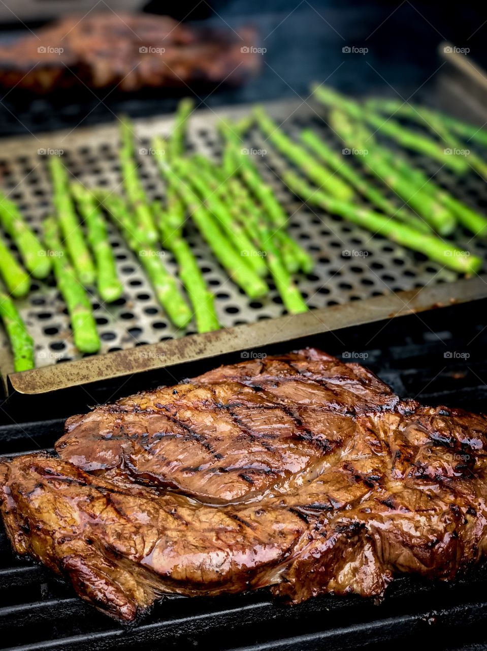 Steaks and veggies on a grill.