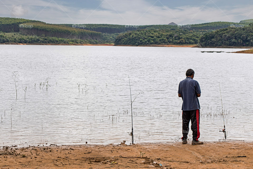 Homem pescando na represa em inteiror de São Paulo.