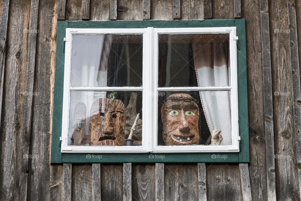 Strange wooden faces looking out through the window 