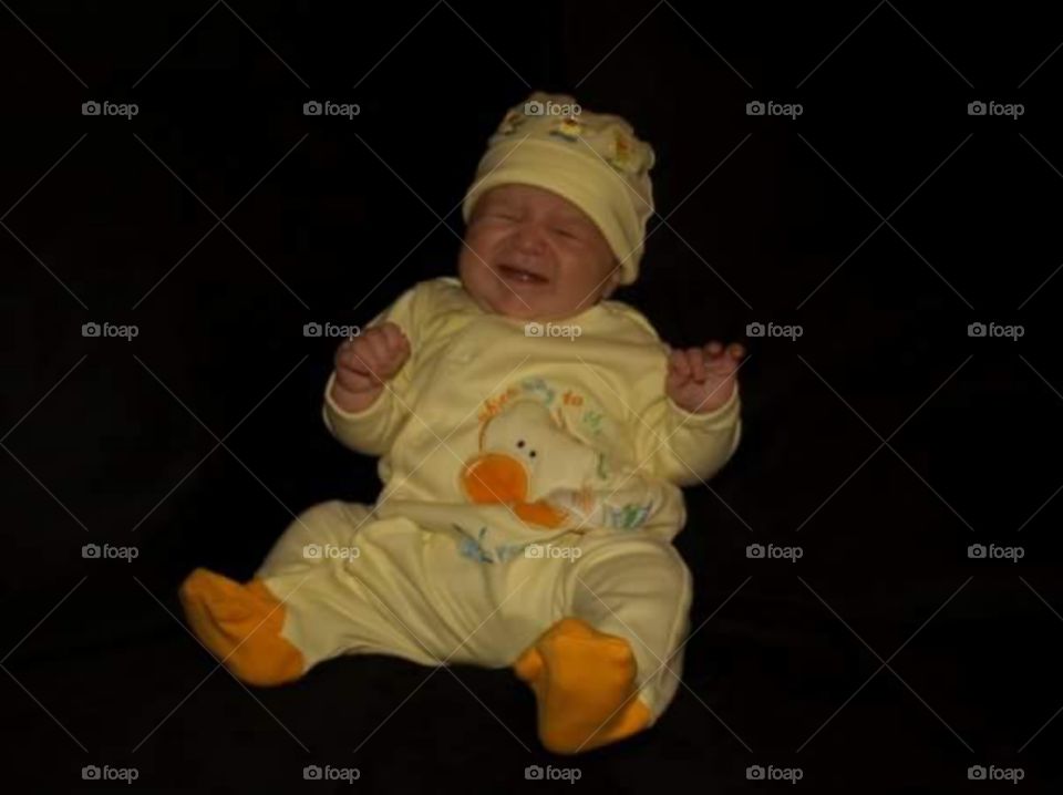 little girl in yellow 2 piece suit , crying. 
isolated on black