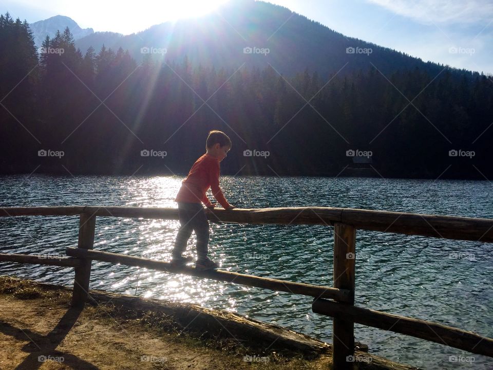 Rear view of boy standing on fence