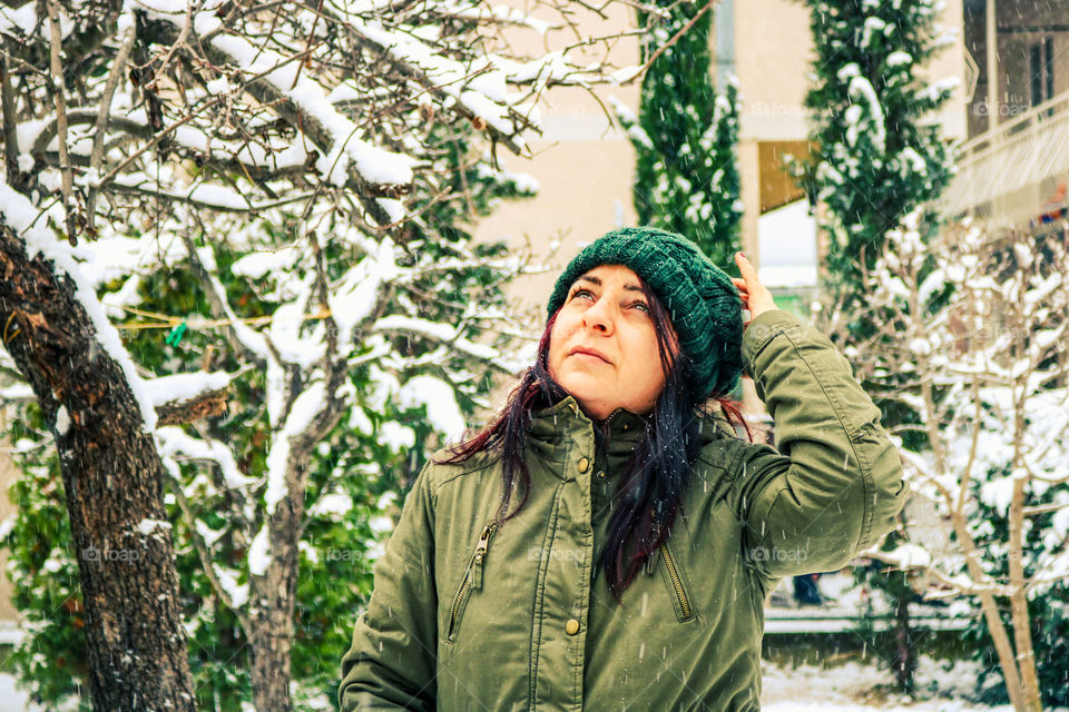 A woman with a knit hat in the backyard while snowing
