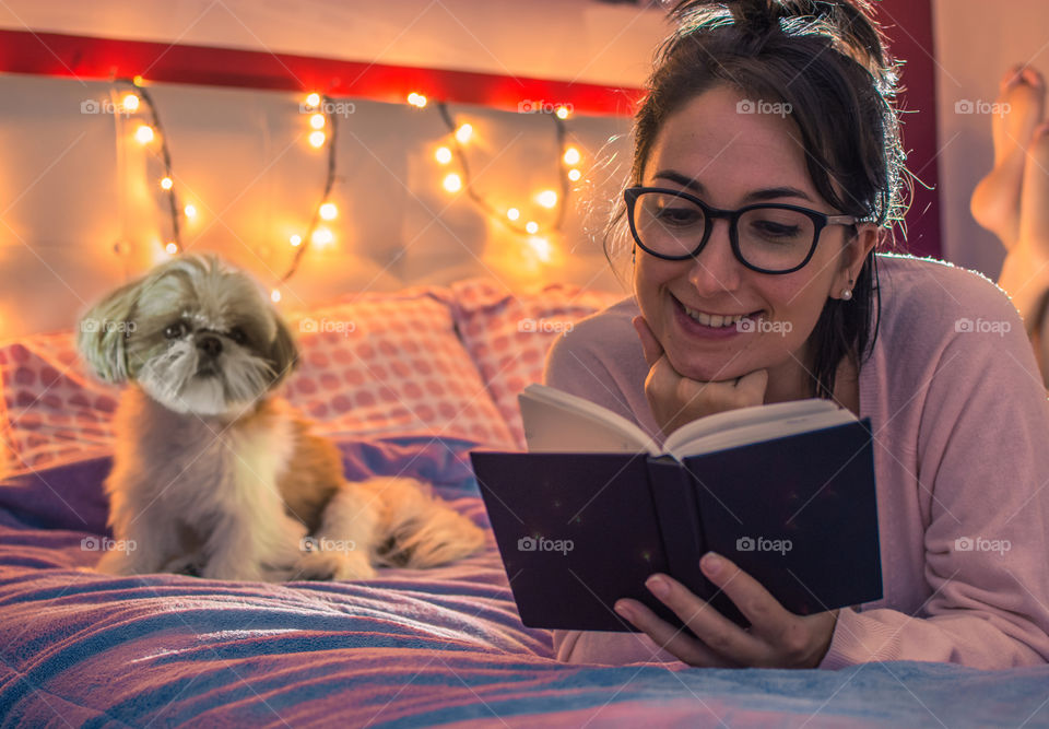 Cute girl reading in bed with her dog