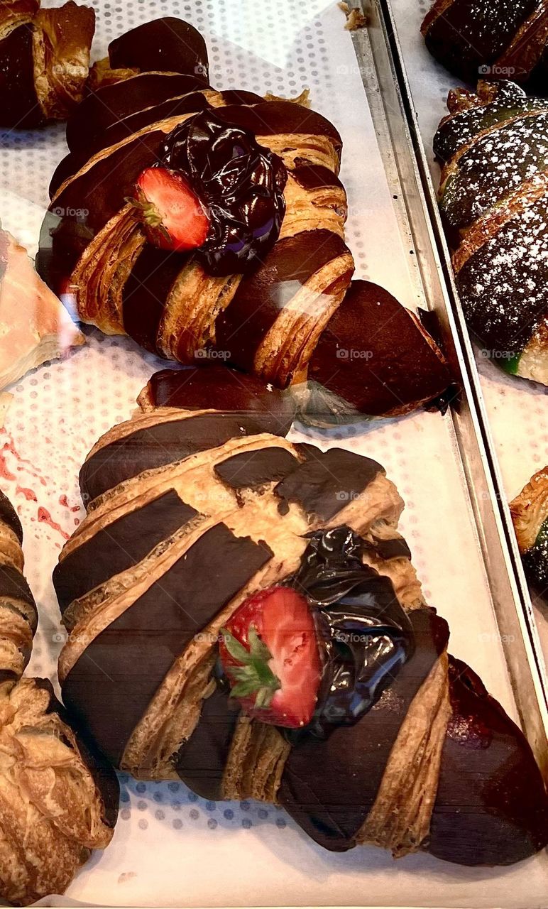 The photo shows delicious croissants generously decorated with chocolate and strawberries