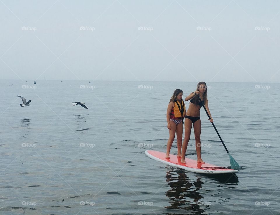 Sisters out on their paddle board in the summer