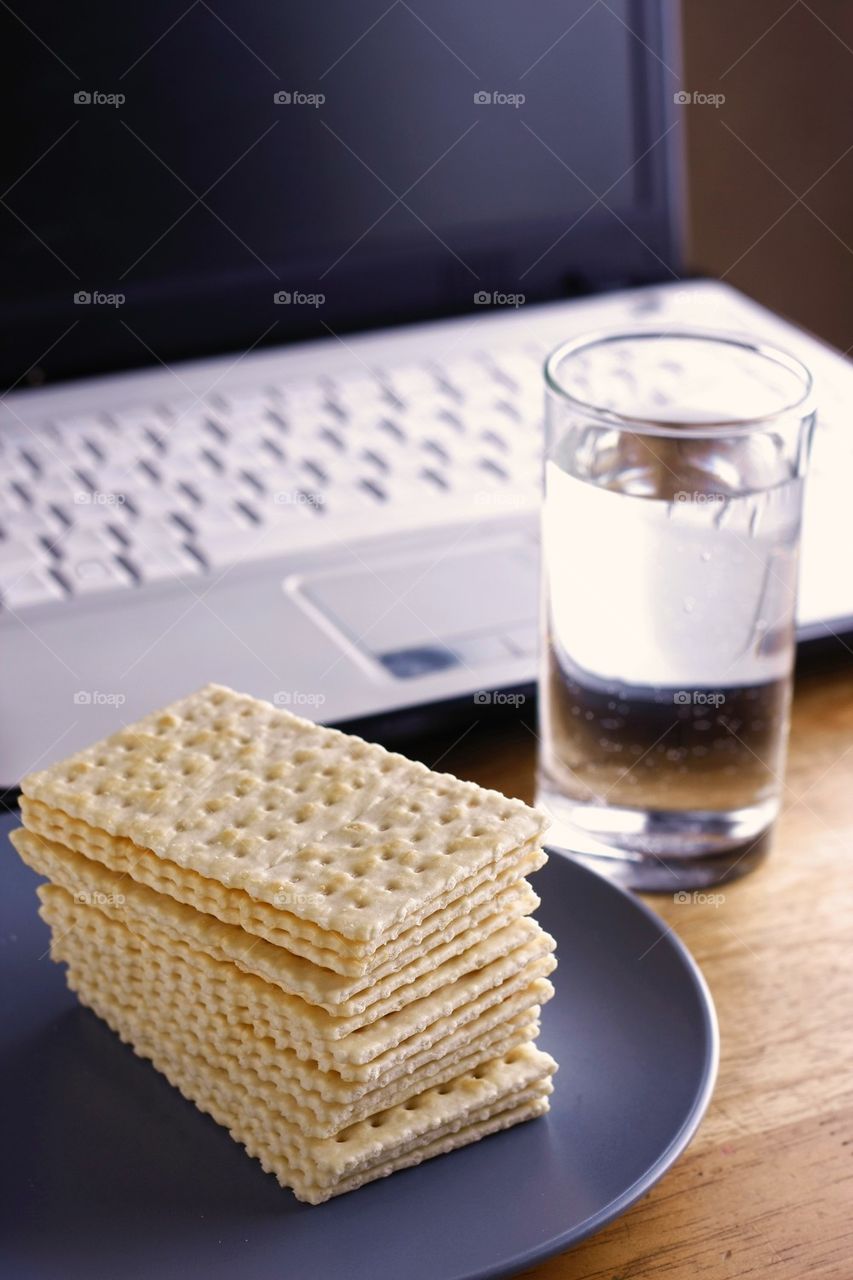 soda crackers, laptop computer and a glass of water