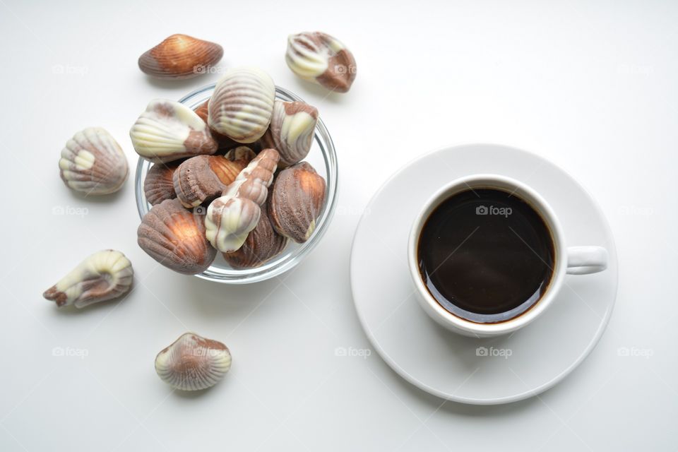 coffee mug and chocolate candies on a white background top view