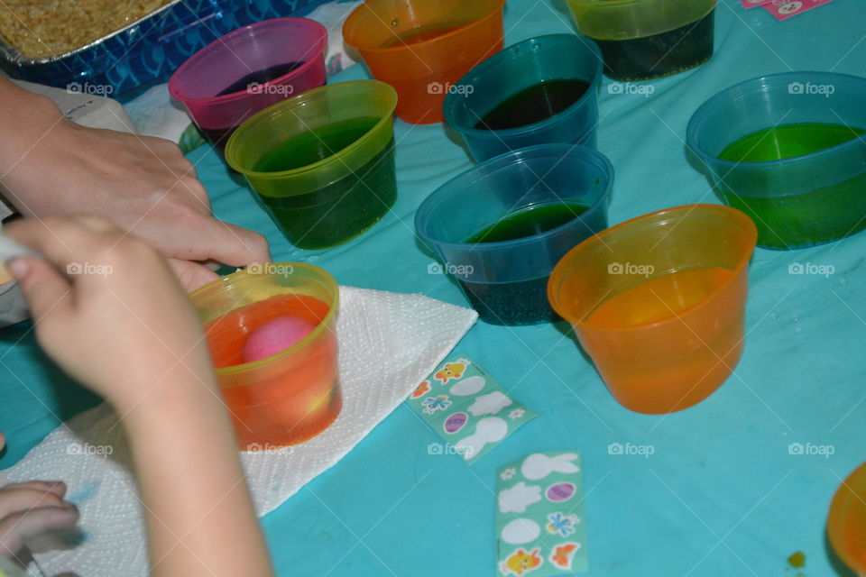 Kids coloring eggs with egg dye for Easter in plastic cups