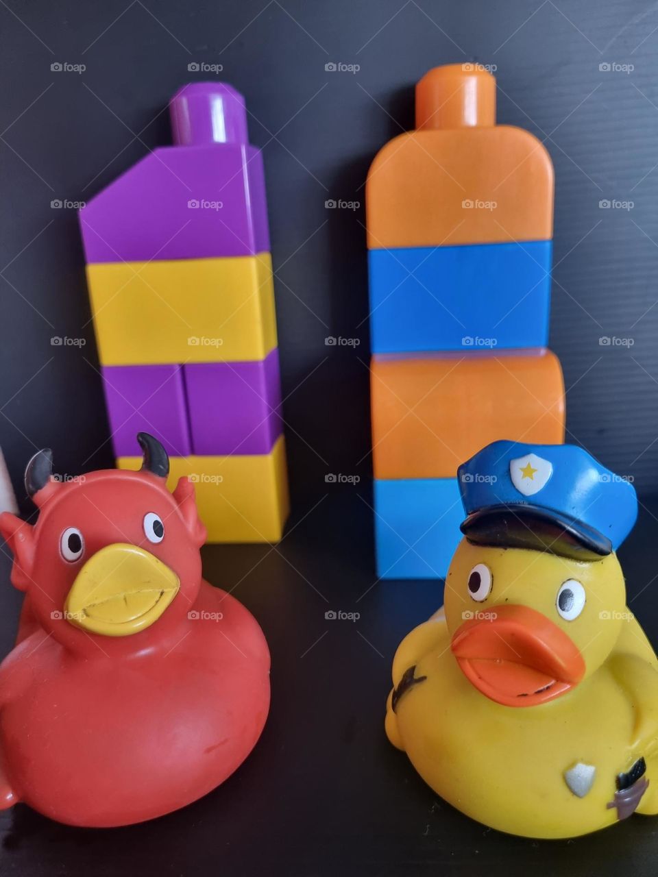 Colorful legos and two ducklings, one of the ducklings is a policeman and the other is a little devil, revealing the difference in character beyond the colors
