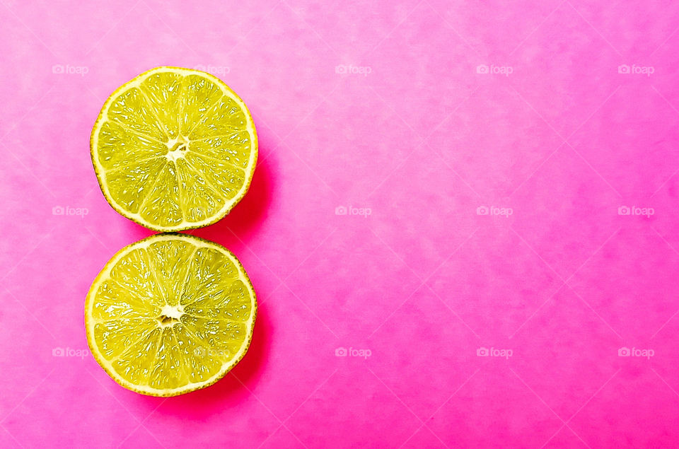 cut limes on pink background as minimalism.