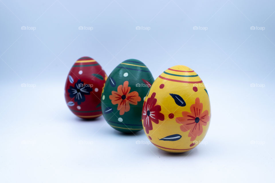 Three different wooden easter eggs with patterns  on moderately lit white background