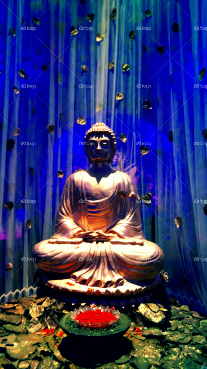 Captured a beautiful sculpture of Buddha with different color effects on background.