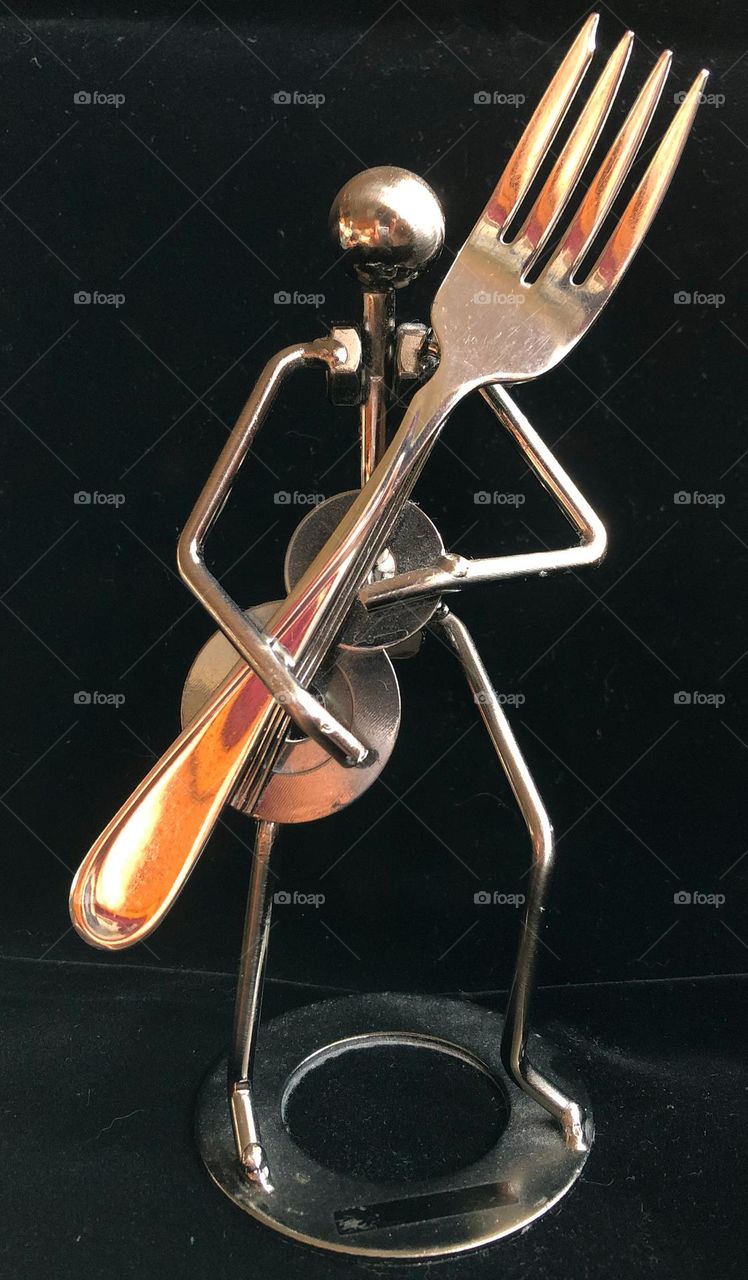 Mr. Forkman not ordinary metal man sculpture holding a fork full frontal view silver chrome fork highlighted 
