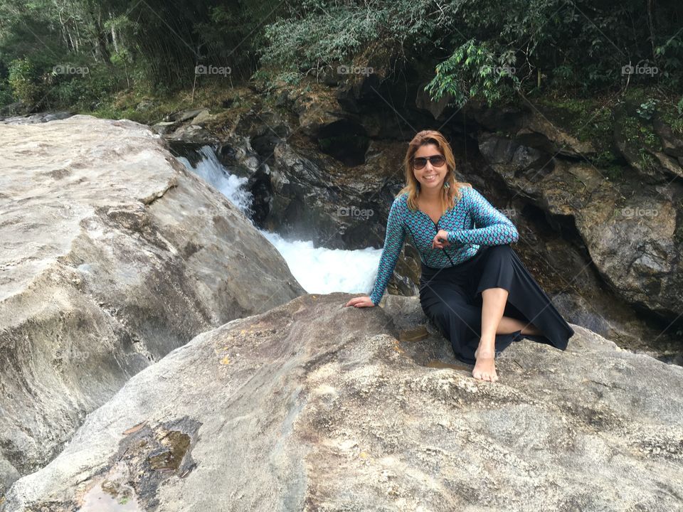 Portrait of woman sitting on rock near stream