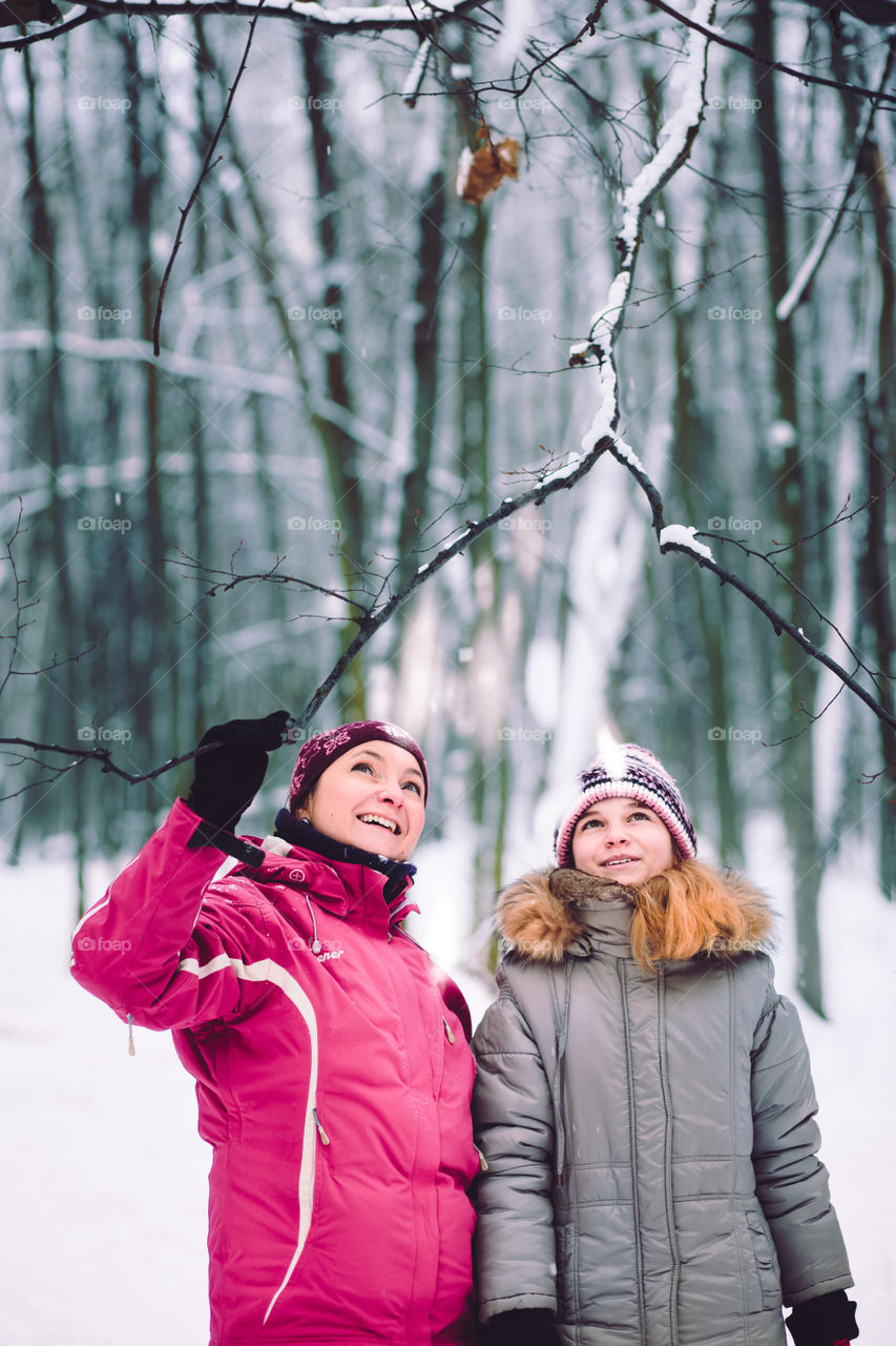 Mother and daughter during the walk in the forest in the wintertime
