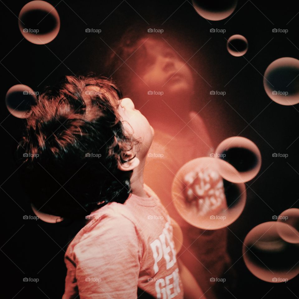 Close-up of bubbles with boy looking up on black background