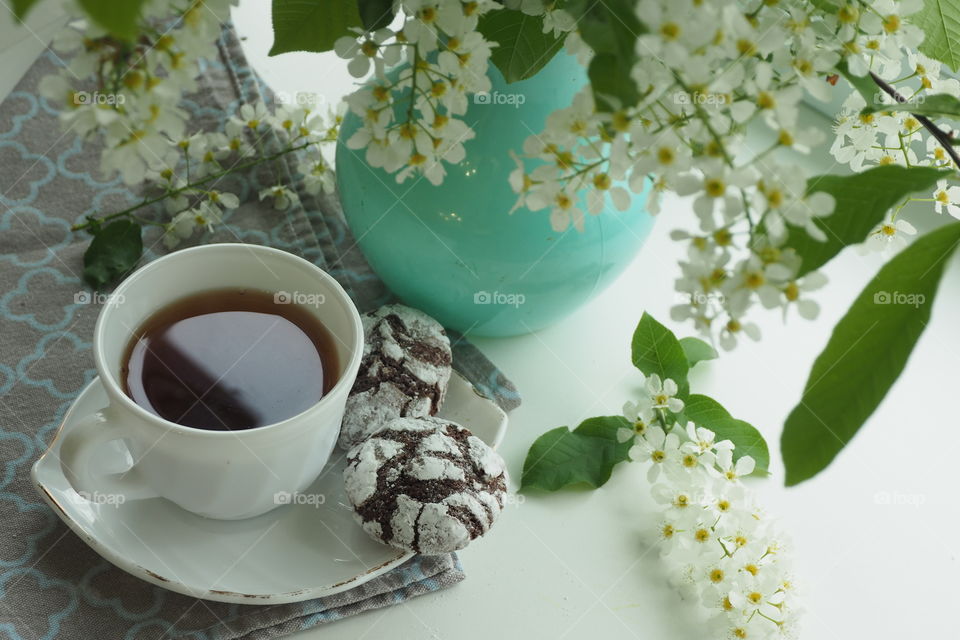 homemade cookies with a cup of tea and a vase with cherry flowers