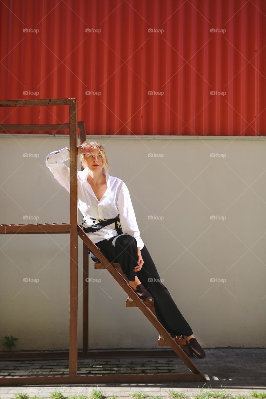 Portrait of Beautiful woman at the street. The girl is wearing a white shirt and black trousers, stylish, beautiful model. Amazing light and atmosphere at thé Autumn vibe