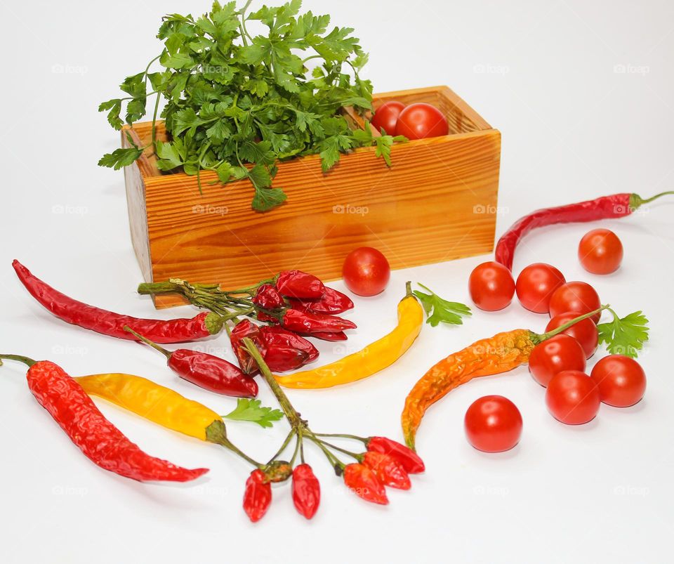 Mandatory ingredients of every kitchen : cherry tomatoes, hot peppers and parsley in a wooden box