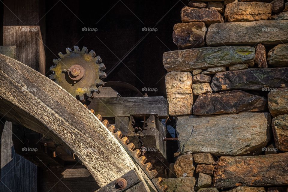 The old rusted metal post pinion is driven by the waterwheel to power mechanisms to grind wheat or corn at the old gristmill. Historic Yates Mill County Park, Raleigh, North Carolina. 