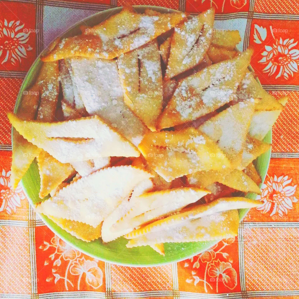 A close-up of the "Chiacchiere" , typical Carnival sweets of Southern Italy, on an orange tablecloth