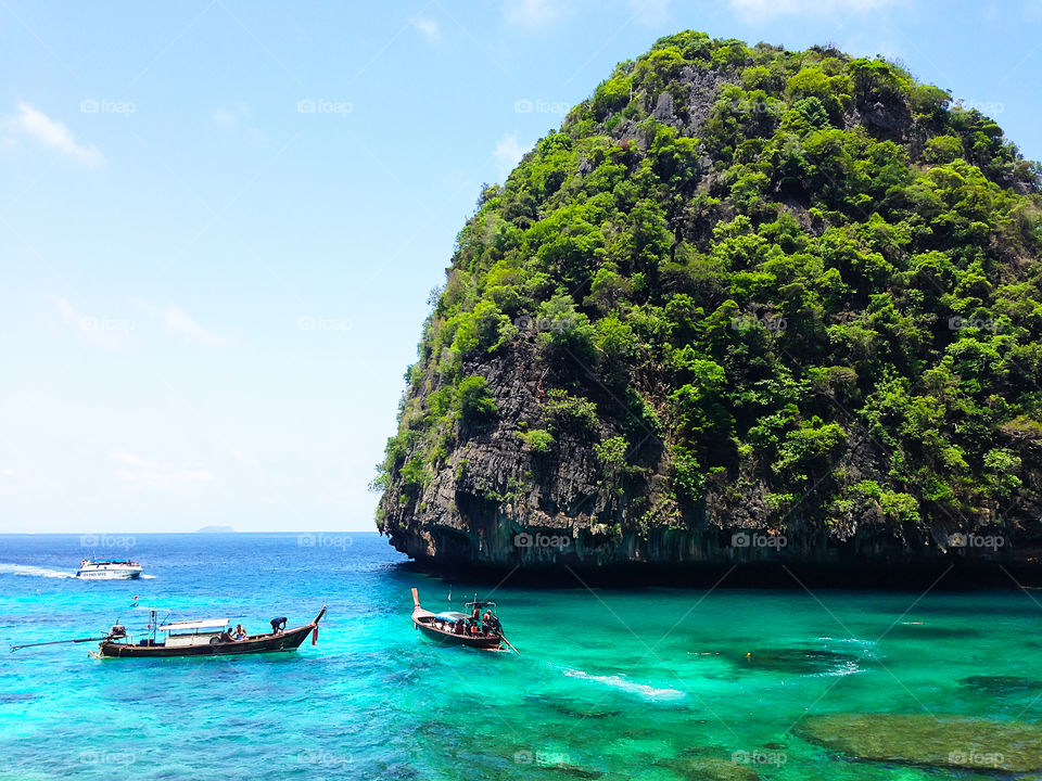 Beautiful view of thai boats nearby green tropical island in the clear turquoise sea water in Thailand 