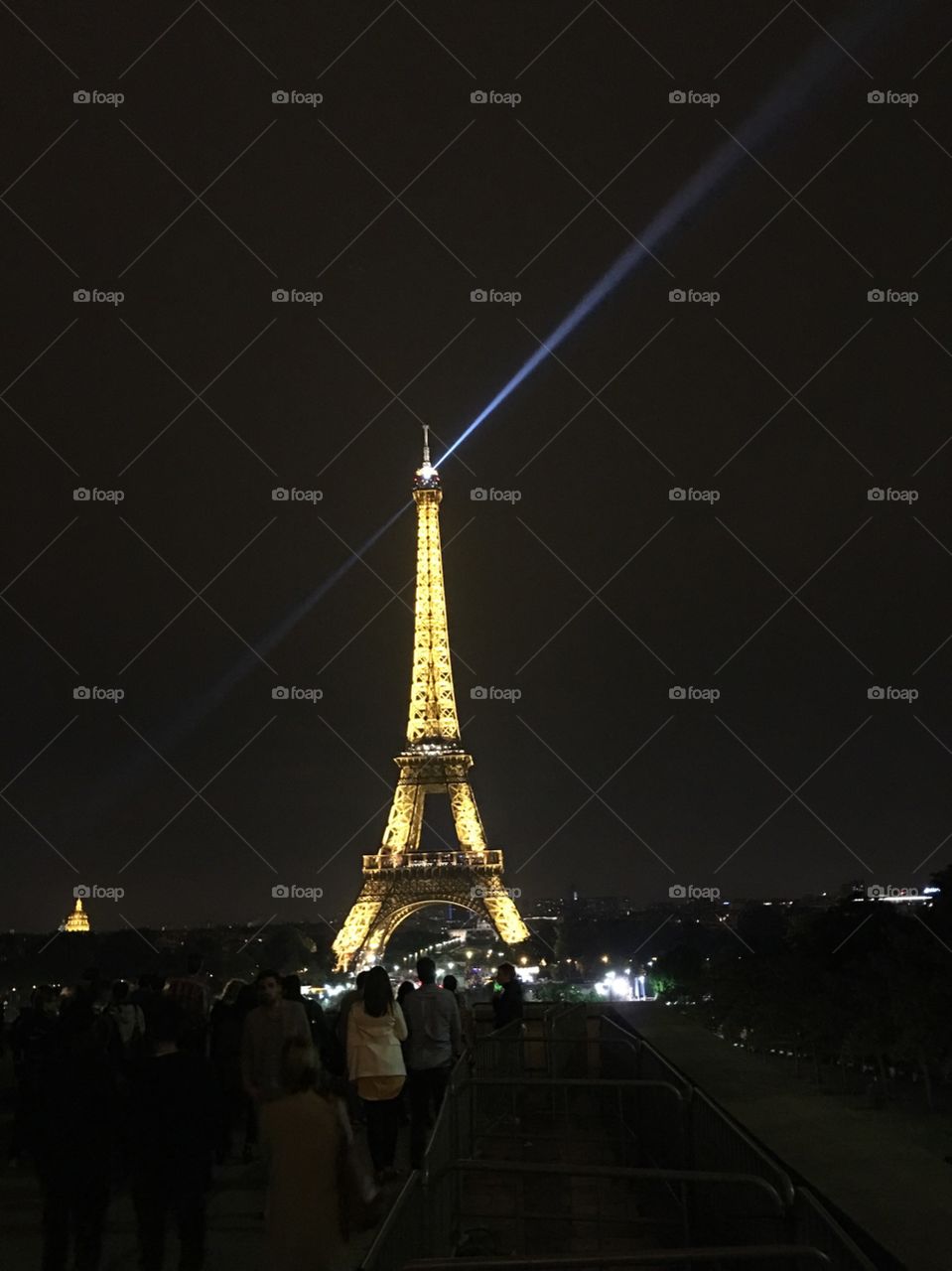Eiffel Tower at night with rotating spotlight at top. 