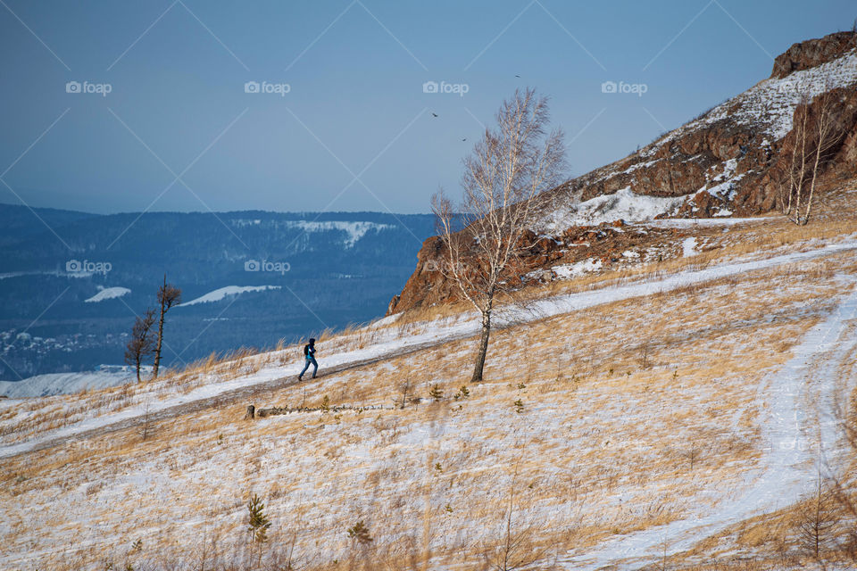 A traveler walks on winter pathway. Winter snowy landscape. Hiking and exploring. Winter activities