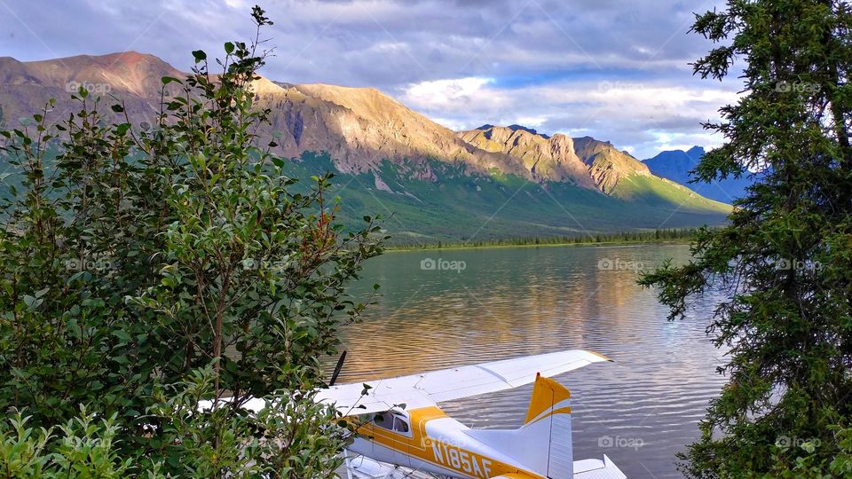 A float plane rests serenely on a remote Alaskan lake, basking in a late evening sunset.