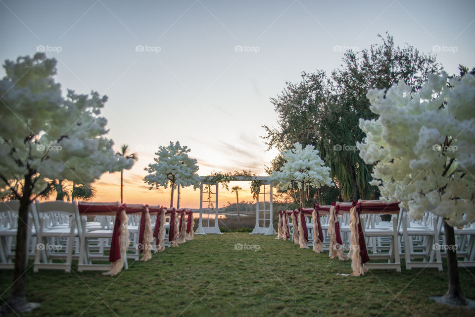 Sunset wedding ceremony with red bows and ribbons