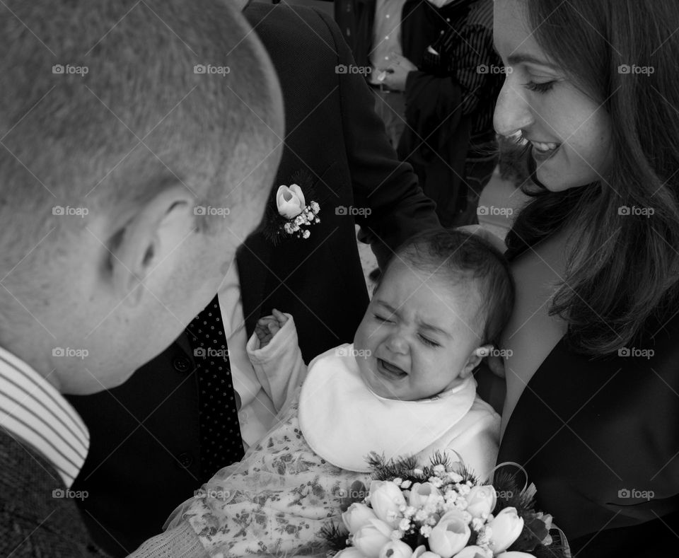 little girl crying while receiving flowers at her baptism