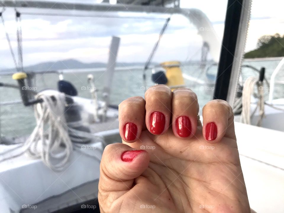 closeup of a hand with red nail polish painted nails