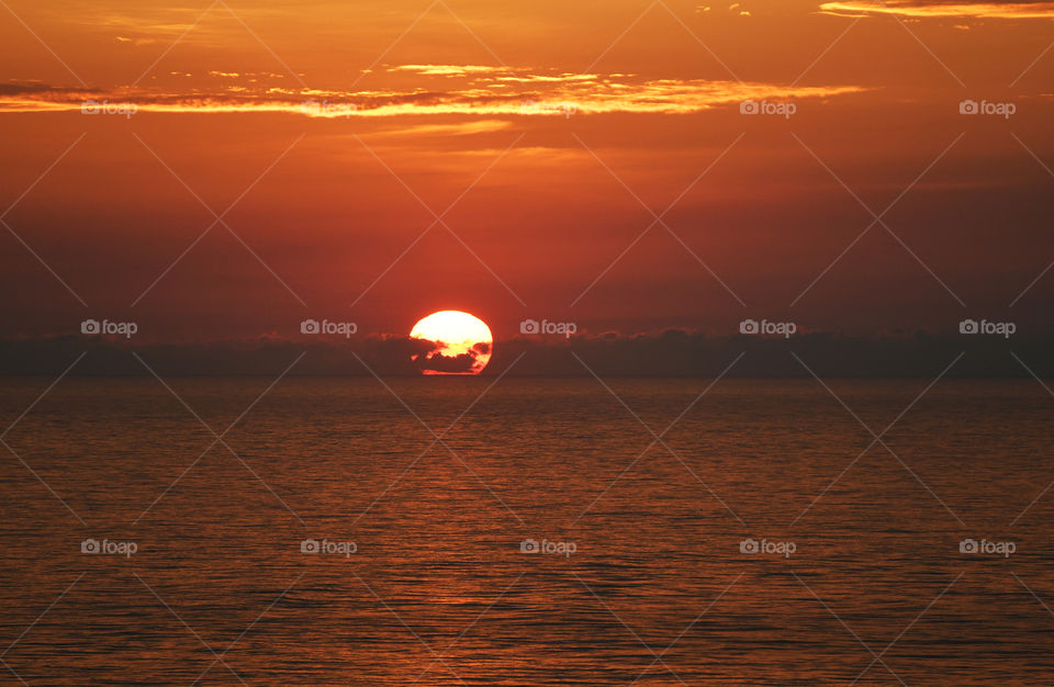 The sun in the far distant Atlantic ocean breaks the horizon during a sunrise to bring in a new day.