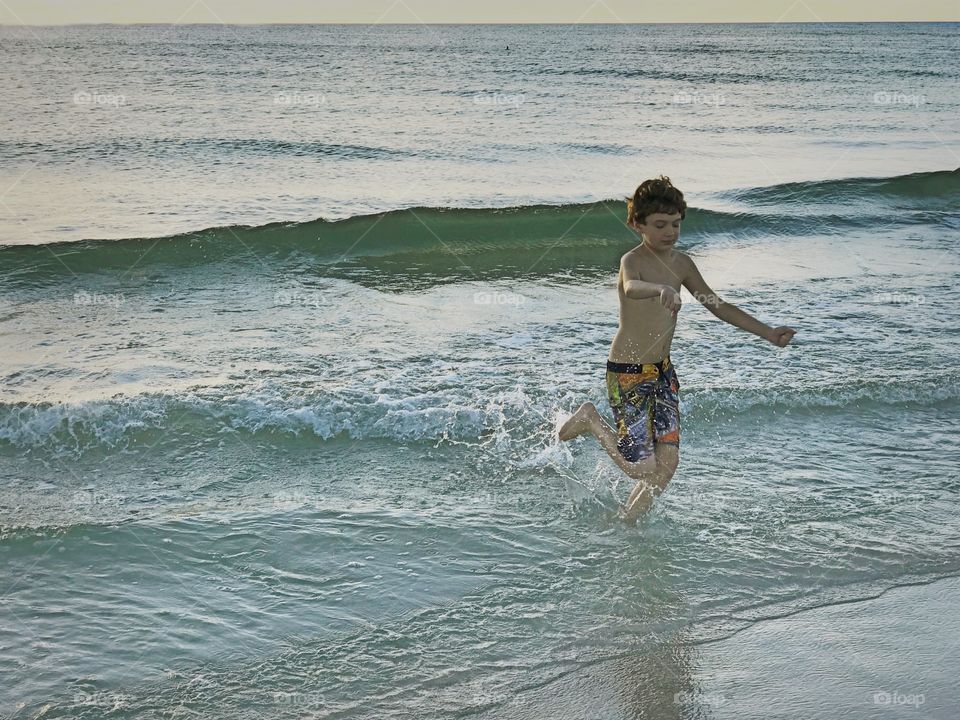Boy joyfully playing in the ocean.