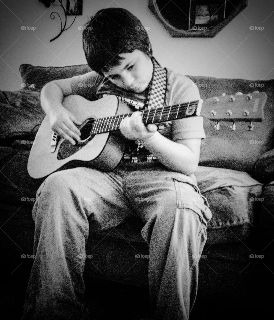 Boy sitting on sofa playing guitar