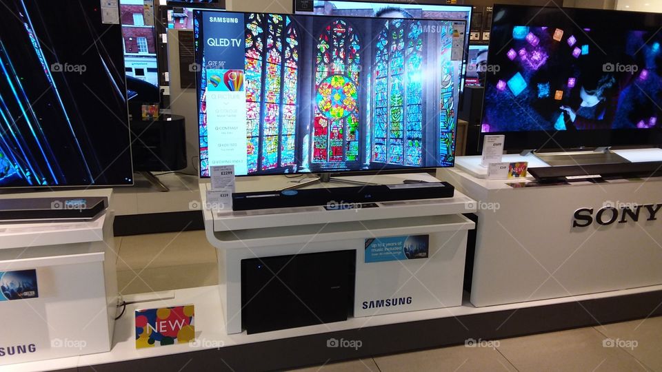 Samsung QLED television with soundbar and sub-woofer on plinths