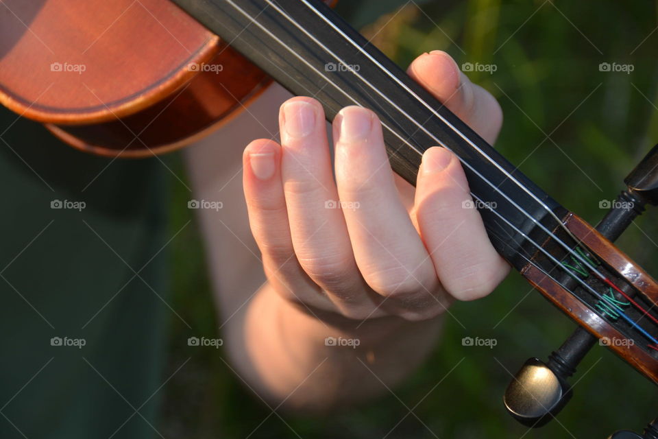 Violin practice close-up hands playing outside green background