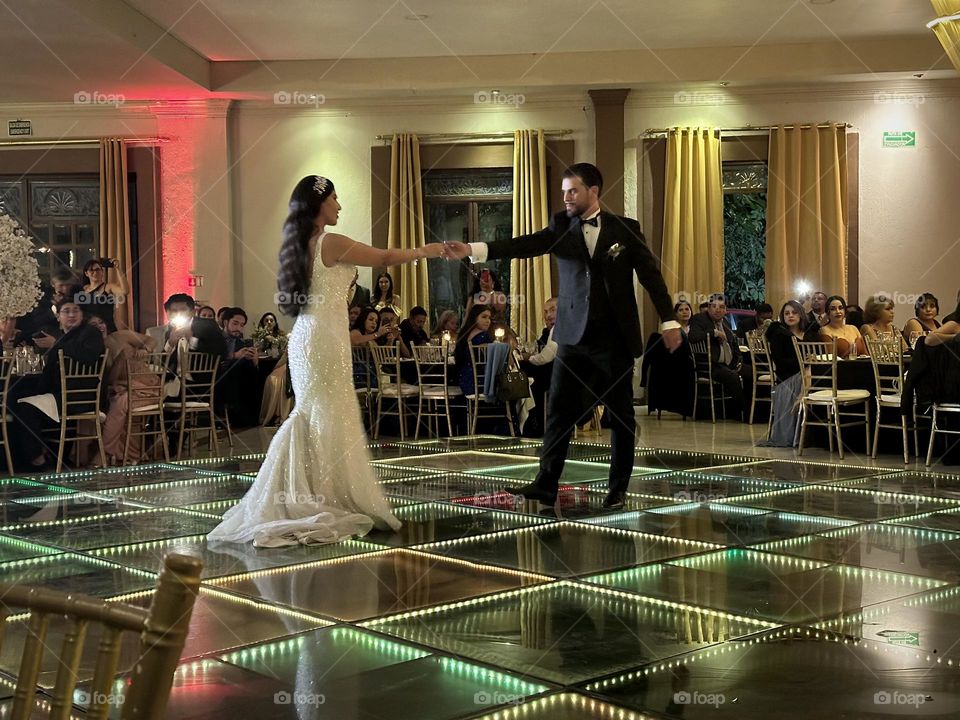 Husband and wife dancing on a luminous platform for the first time on their wedding.