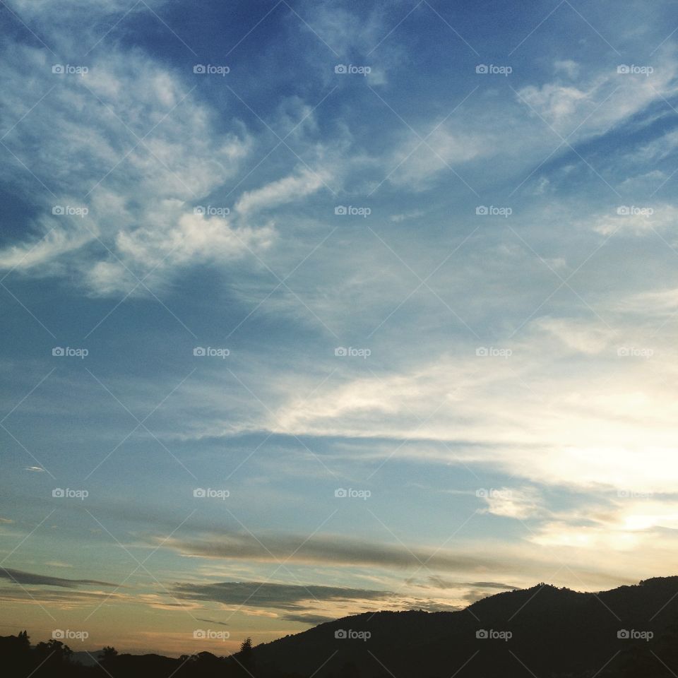 Silhouette of mountains against cloudy sky during sunrise