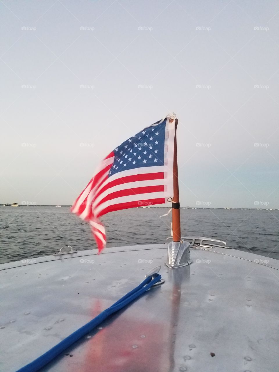 American flag flying over a vintage aluminum boat on the water