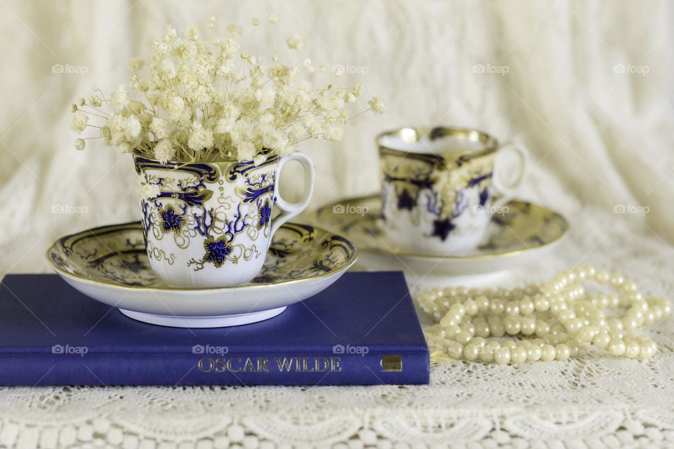 Victorian teacups with dried flowers, pearls and book