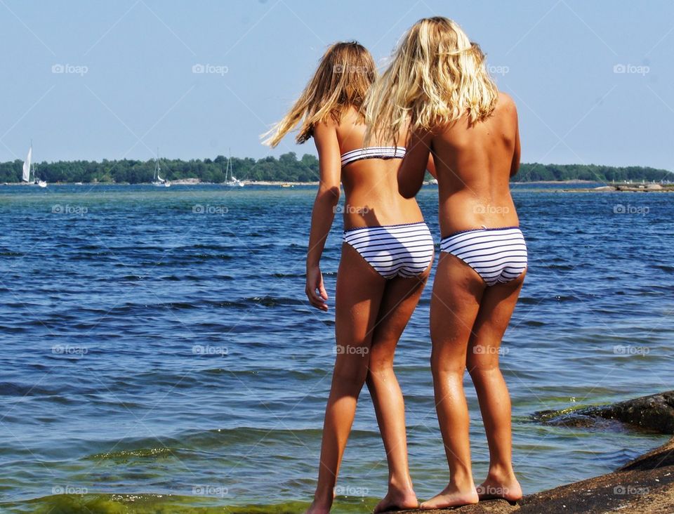 Rear view of two women standing at beach