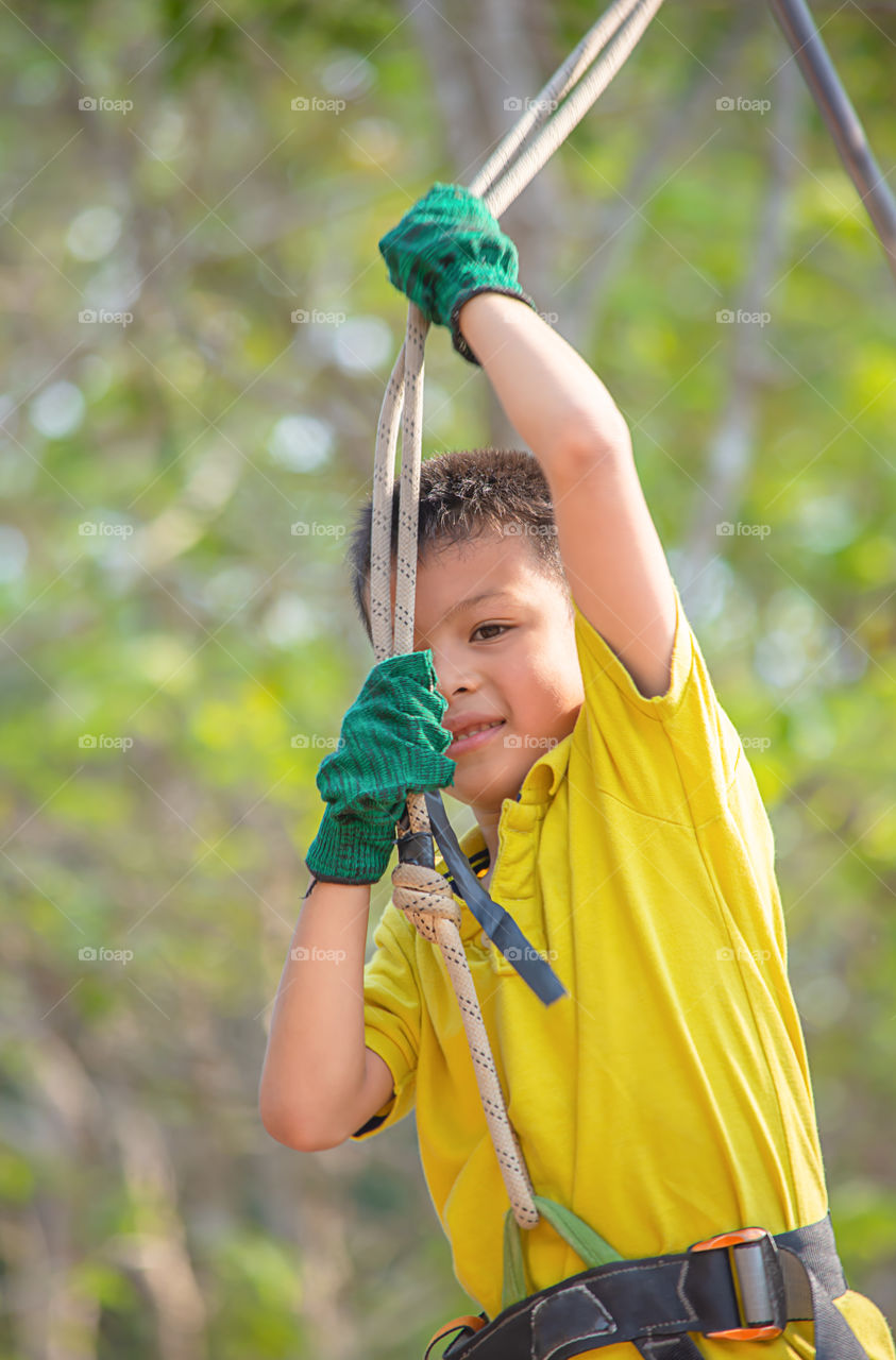 Asean boy nodes the rope and smiling happily background blurry tree.