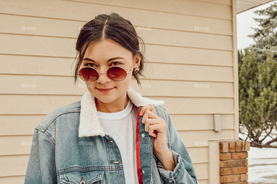 Cool and trendy portrait of a woman wearing denim and retro sunglasses 