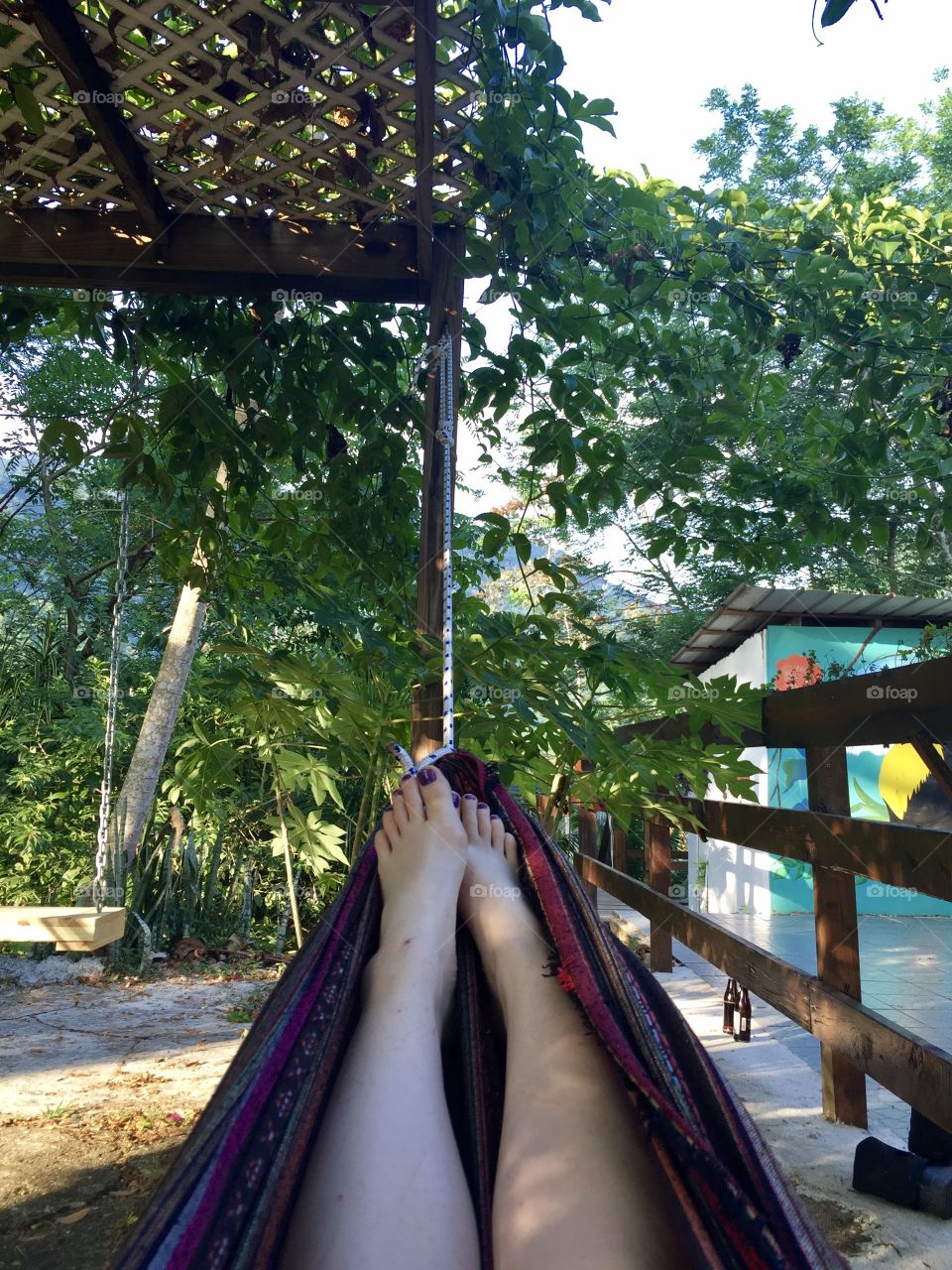 The legs of a girl laying in a hammock