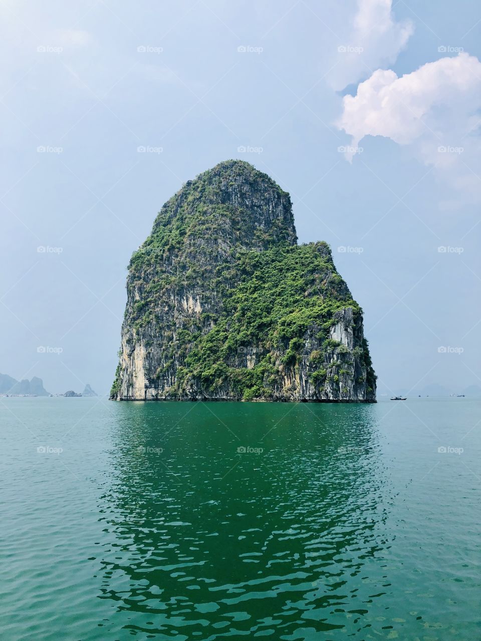 An island jutting out of the ocean in Halong Bay.