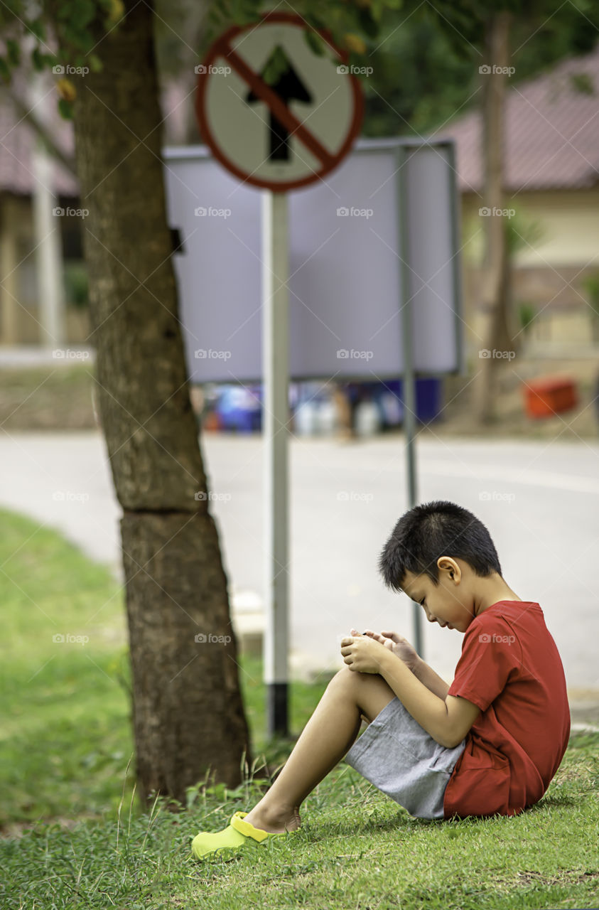 Asian Boys play telephone on the lawn Background blurry image of road