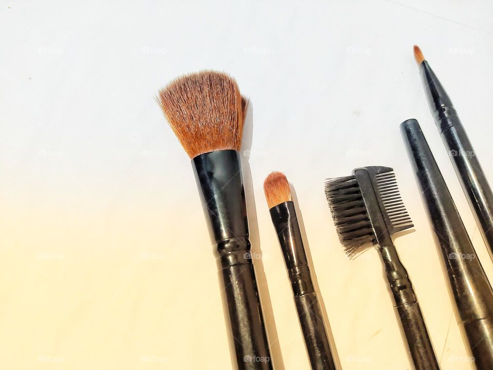 Makeup brushes isolated on white and yellow background