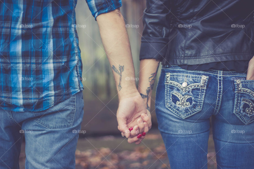 Man and woman holding hands shot from behind with tattoos